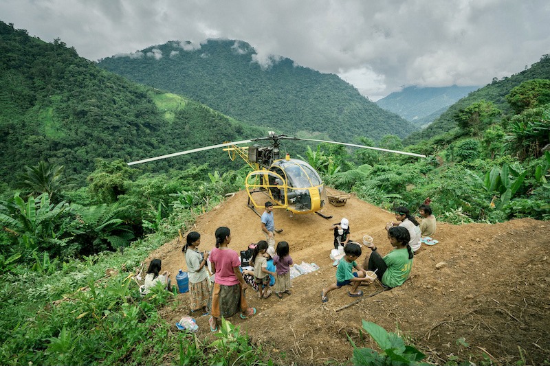 The PAMAS "Yellow Bee" helicopter landed on an improvised mountain helipad, observed by local children in the Philippines.